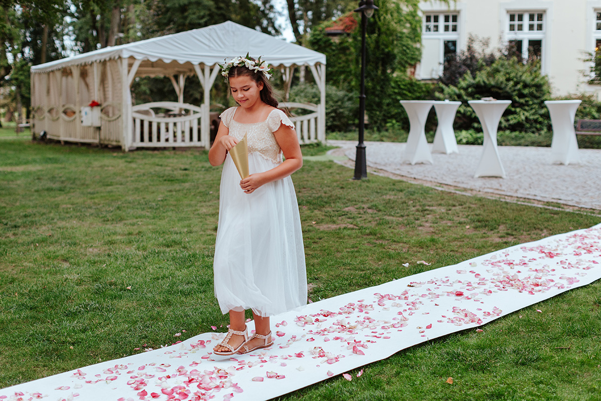 dziewczynka sypie płatkami kwiatów na weselu